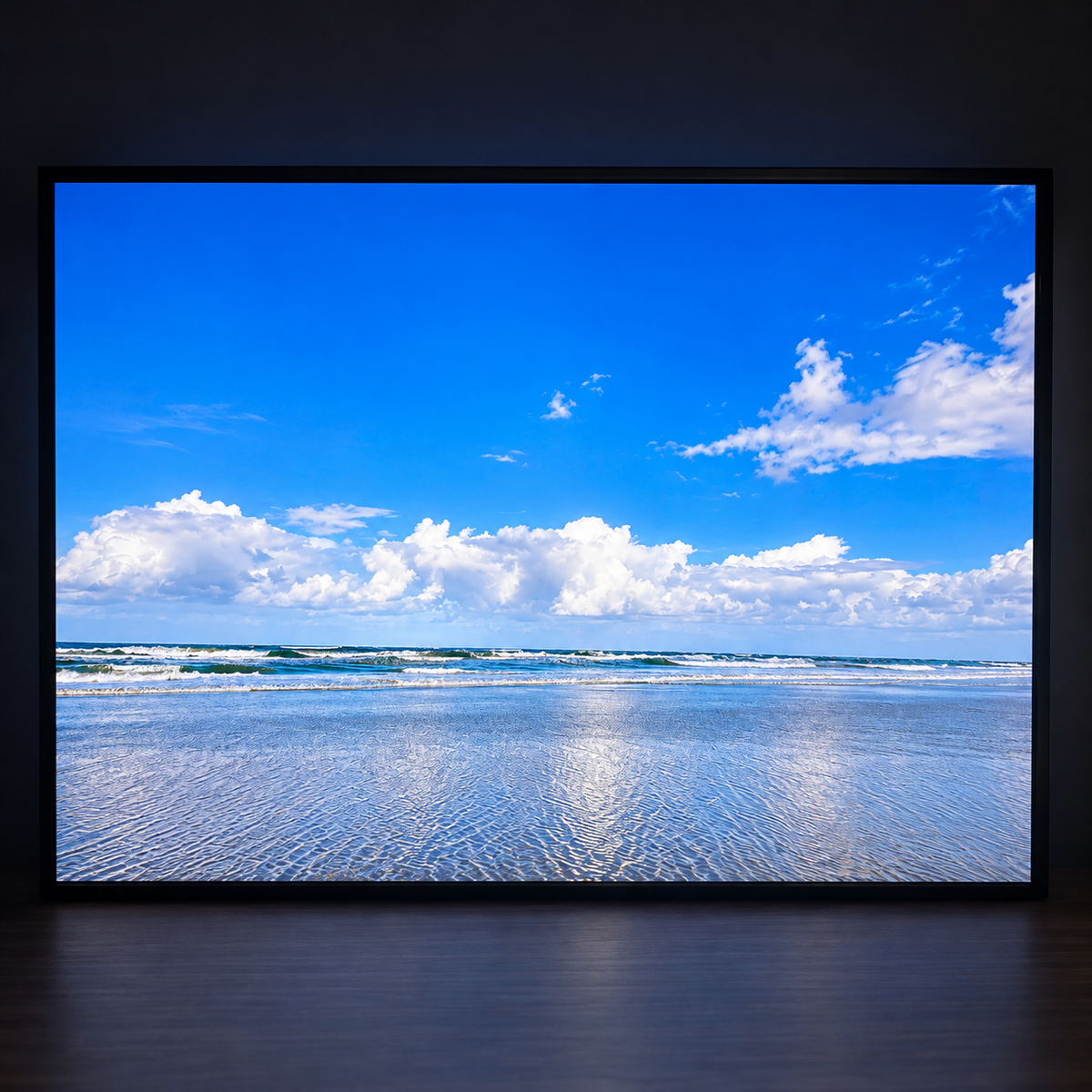 Illuminated wall art showing a bright blue ocean horizon with white clouds and reflective wet sand