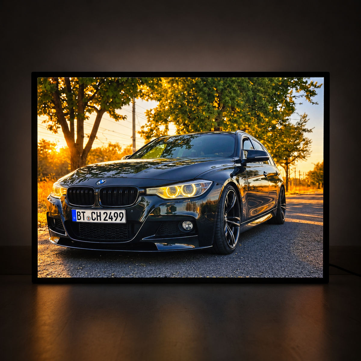 Illuminated photo lightbox featuring a black BMW at sunset