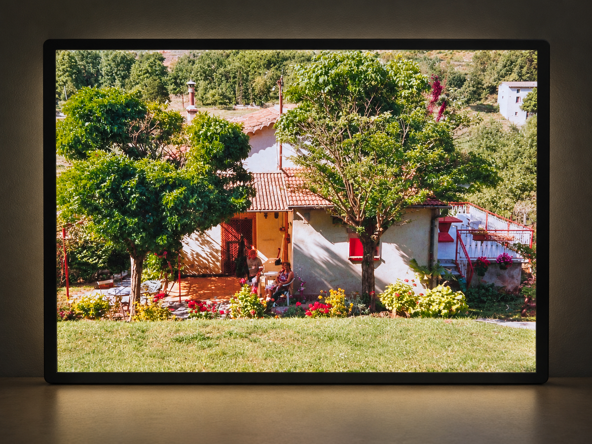 Illuminated photo lightbox featuring a sunny garden with trees and a house