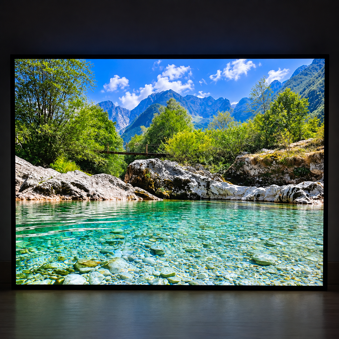 Illuminated wall art showing a crystal-clear mountain river with rocks, trees and rugged peaks
