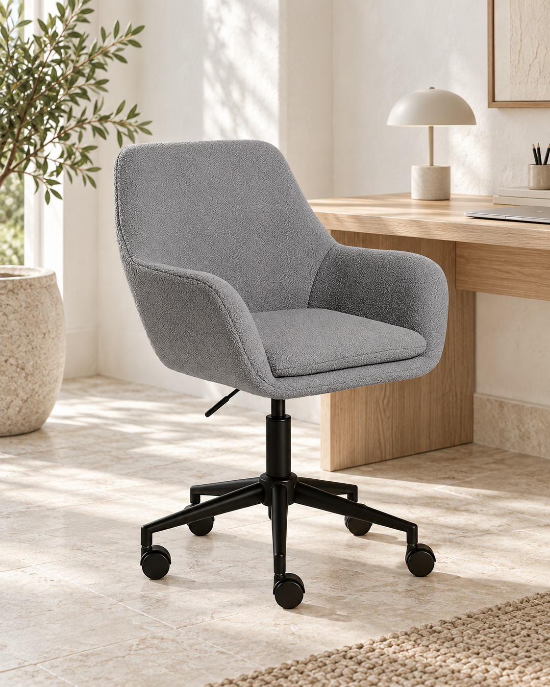 Grey bouclé desk chair with black wheeled base in a bright home workspace